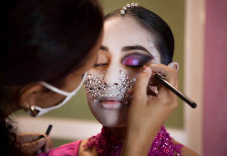 Makeup artist with a mask painting a woman's face for halloween