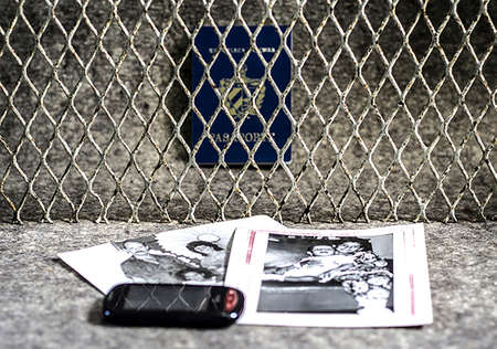 Havana Cuba. 01/01/2019. A fence dividing a Cuban passport from some photos of a family and a cell phone. Divided familyのeditorial素材