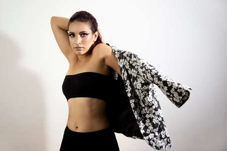 Young girl posing for a photo shoot dressed in black putting on a black and white patterned jacket...