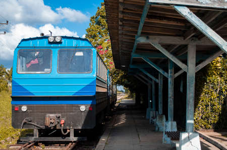 Blue wagons of an old train on the lines in a country town, parked on an old platform, sunny day