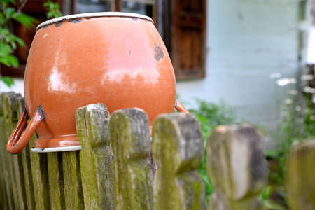 old metal pot hanging on a wooden fence