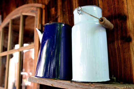 Old white milk bubble standing on a wooden shelf and blue jugの写真素材