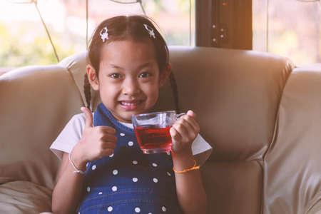 Smile Little Girl holding red juice in the glass .Vintage style.の写真素材