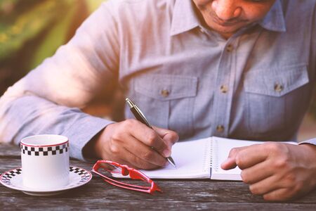 Businessman Hands writing with coffee and glasses.の写真素材