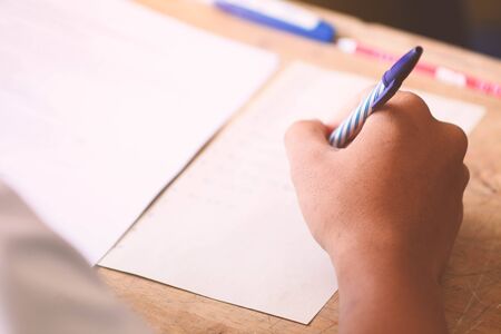 Close-up of writing hands of uniform students to test at school.