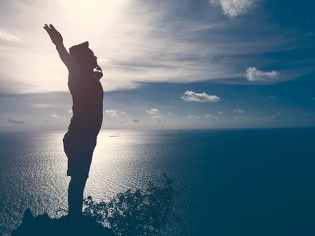 Man hiking silhouette in mountains, sunset and ocean. Man hiker  on top of mountain looking at...
