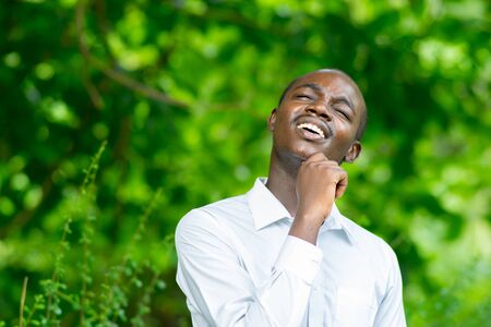 Smile african portrait man thinking in green nature background.の写真素材
