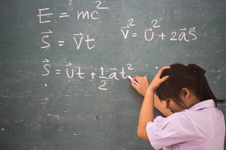 Serious girl student about  physics formula in classroom.の写真素材