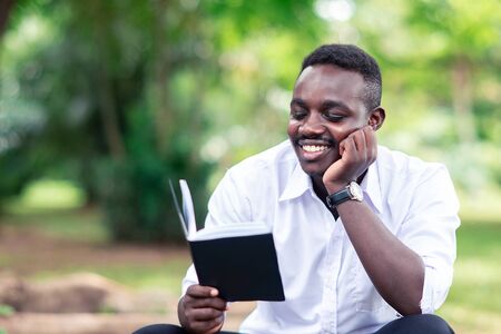 African man reading a book in the park