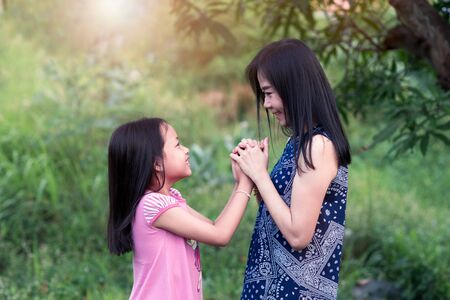 Mother and daughter looking eyes and holding hands with loveの写真素材