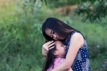 Asian mother and daughter hugging with love  in the parkの写真素材