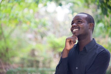 African business man thinking and smiling in green nature background.の写真素材