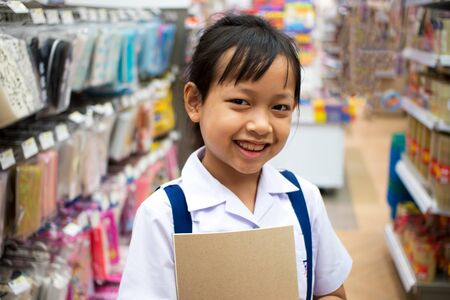 Asian uniform student girl in stationery store buying pens and school supplies. Back to school concept.の写真素材