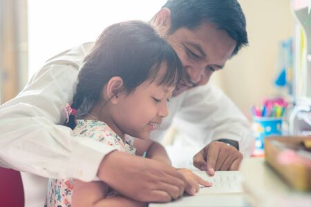 Father helping her daughter for her homework with funnyの写真素材