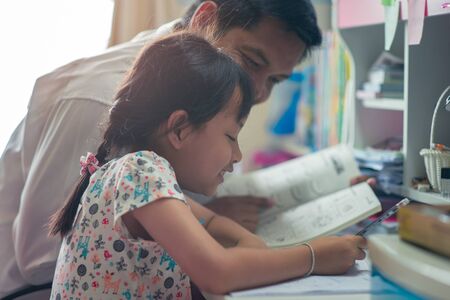 Father helping her daughter for her homework with funnyの写真素材