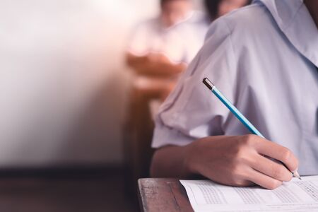 Exam with uniform school student doing educational test with stress in classroomの写真素材