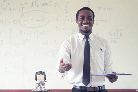 African science teacher teaching in the classroom with microscope.の写真素材