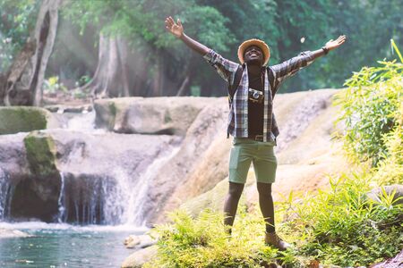African Man Traveler with backpack standing and relaxing freedom at waterfallの写真素材