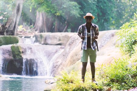 African Man Traveler with backpack standing and relaxing freedom at waterfallの写真素材