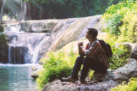 Traveler man with backpack holding camera with green natural background.の写真素材
