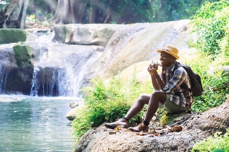 African Man Traveler with holding film camera and relaxing freedom at waterfallの写真素材