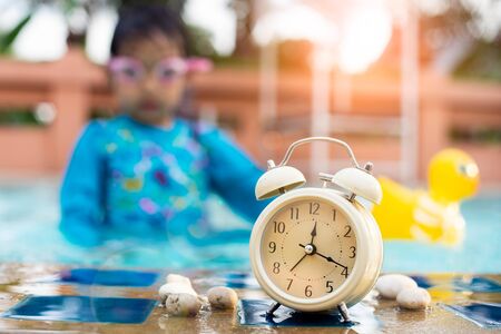 Retro Alarm clock  at the swimming pool with children wearing swim goggles.