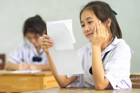 Students writing pen in hand doing exams answer sheets exercises in classroom with not stress.の写真素材