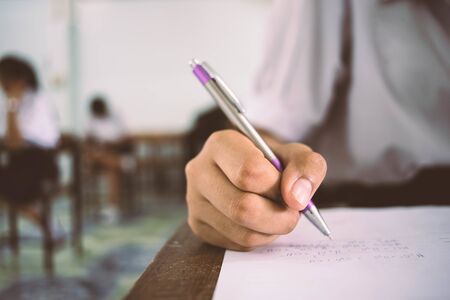 Close up Students writing and reading exam answer sheets exercises in classroom of school with...
