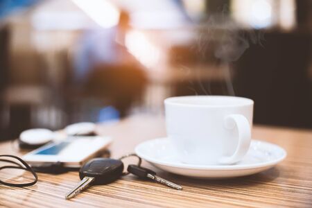 Cup of hot coffee , Key and smartphone in cafe.Selective focus