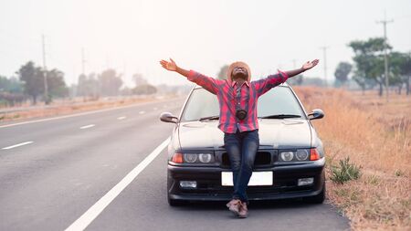 Freedom African traveler man holding camera with sitting on the carの写真素材