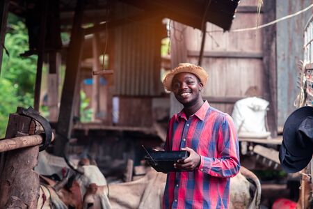 African farmer man with retro radio broadcast receiver on shoulder stands happy smiling outdoor on...
