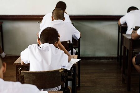 Students taking exam with stress in school classroom.の写真素材