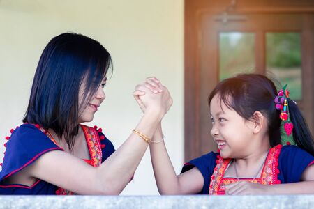 Asian daughter and mom arm wrestling having fight confrontation or family conflict with fun and happy.の写真素材