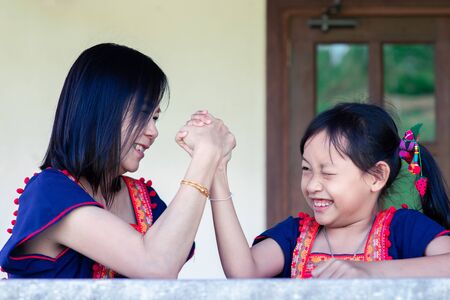 Asian daughter and mom arm wrestling having fight confrontation or family conflict with fun and happy.の写真素材
