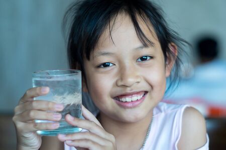 Smile asian child girl hold a glass of ice waterの写真素材