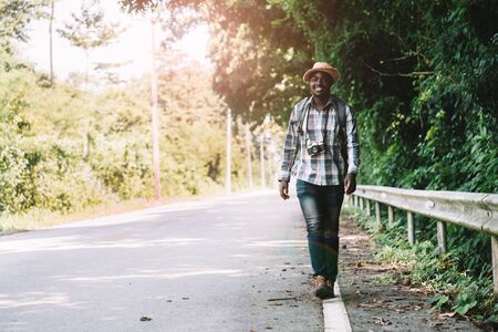 African man travel carrying backpack walking on the highway roadの写真素材