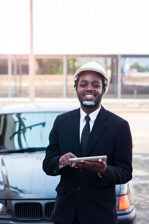 African man construction engineer worker standing and use teblet with the carの写真素材