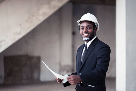 African man construction engineer worker standing and looking the unfinished buildingの写真素材