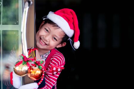 Asian smiling beautiful girl behind door at home.Christmas or X-mas conceptの写真素材