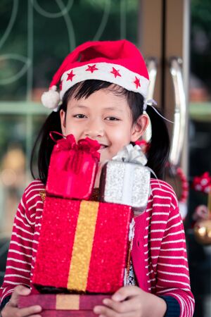 Asian little girl  holding a lot of red gift box with smiling and happy at home.の写真素材