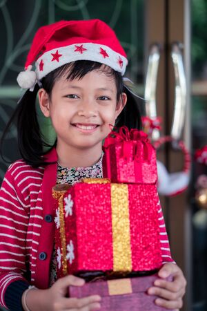 Asian little girl  holding a lot of red gift box with smiling and happy at home.の写真素材