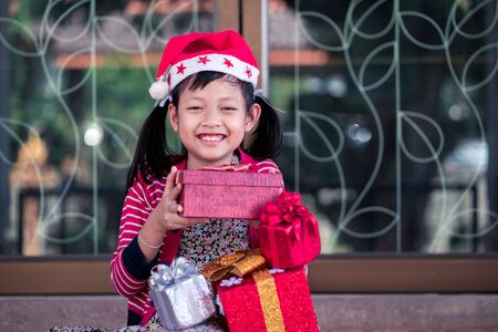 Asian little girl  holding a lot of red gift box with smiling and happy at home.の写真素材