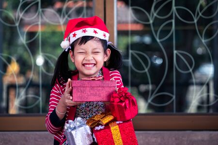 Exciting asian little girl  holding a lot of red gift box with smiling and happy at home.の写真素材