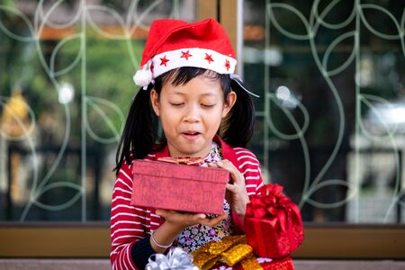 Exciting asian little girl holding red gift box with smiling and happy at home.の写真素材