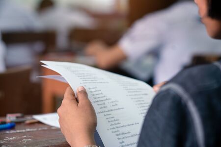 Student reading and doing test or exam  in classroom of school with stressの写真素材