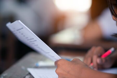 Student reading and doing test or exam  in classroom of school with stress
