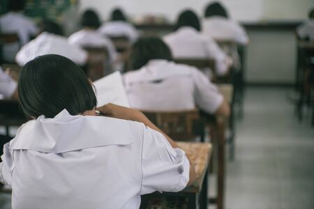 Student reading and doing test or exam  in classroom of school with stressの写真素材