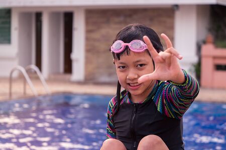 Cute little child girl with goggles in swimming poolの写真素材