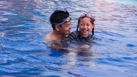 Laughing daughter and father smiling  in swimming pool