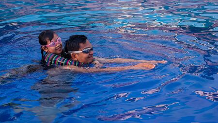 Happy asian father with little daughter in swimming pool at water parkの写真素材